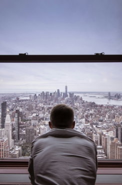 man in gray shirt looking at city buildings during daytime
